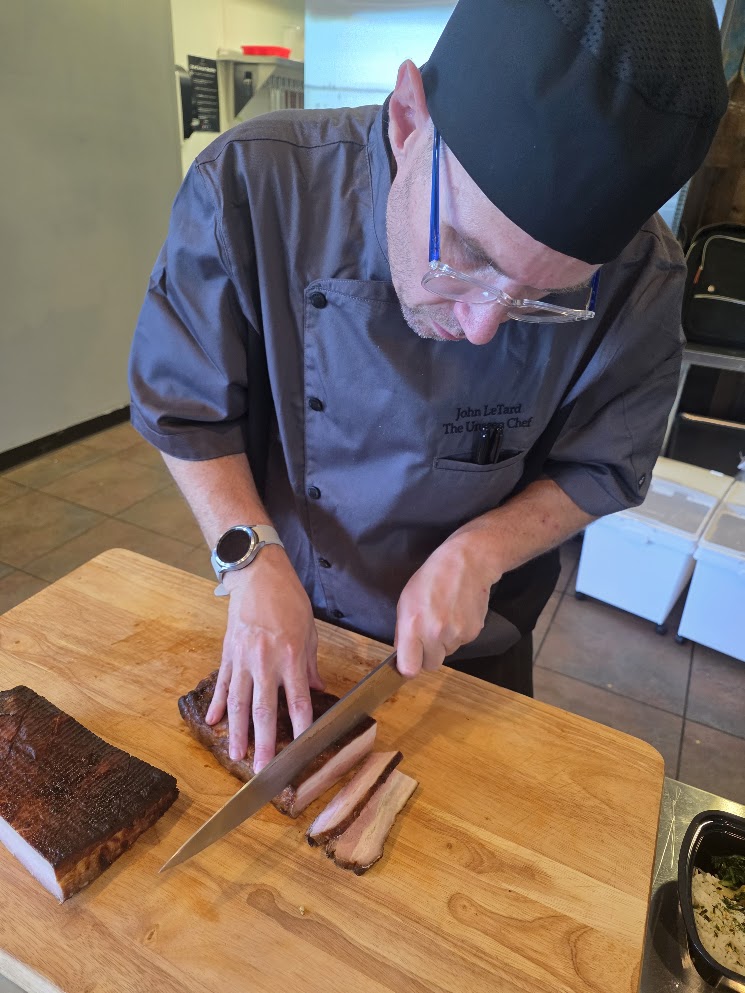 Chef John slicing freshly cooked pork belly in the kitchen