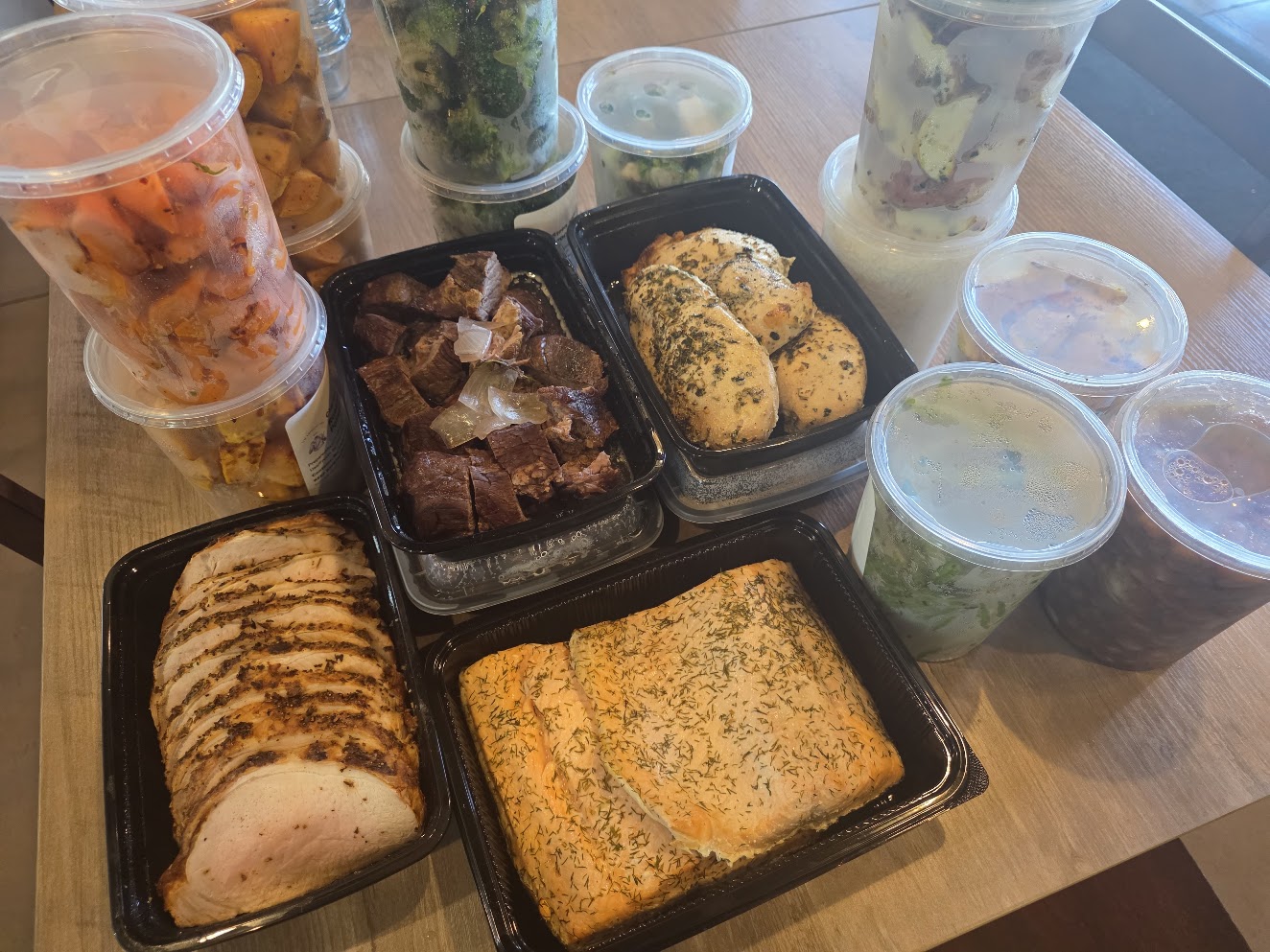 Bulk meal prep with sliced proteins, salmon, roasted potatoes, and prepared vegetables ready to portion